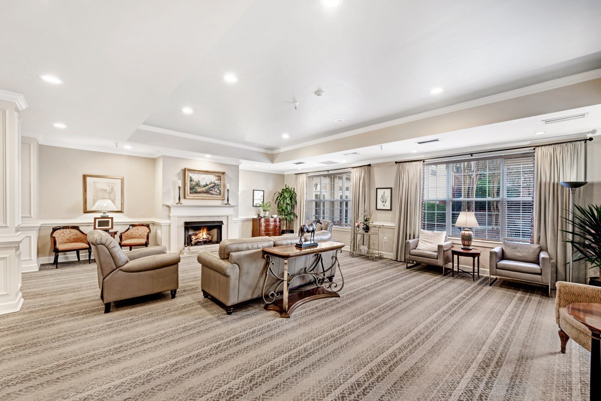A spacious and elegantly designed living room featuring comfortable sofas, a central coffee table, and a cozy fireplace.