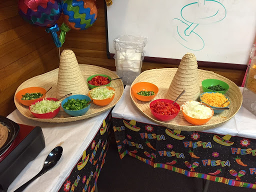 A vibrant taco bar setup featuring cone-shaped tortilla shells and a variety of fresh toppings.