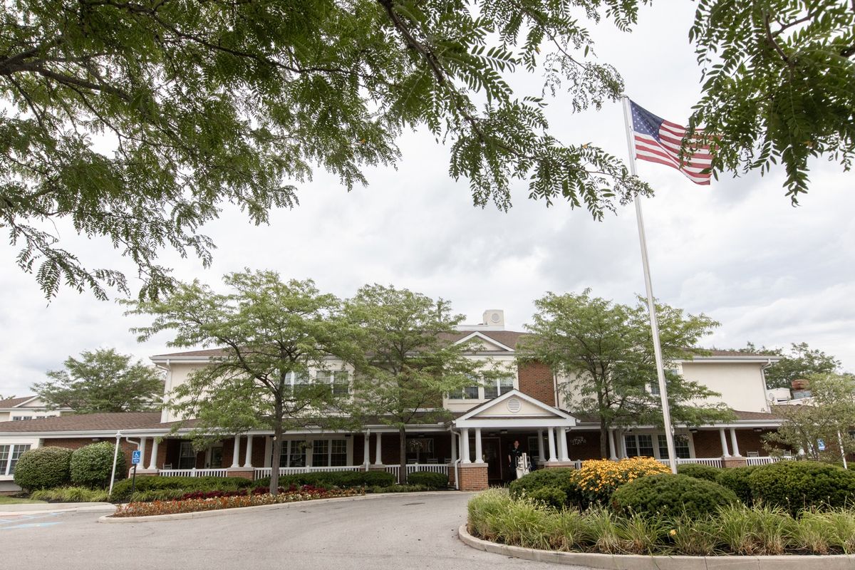 A view of a building surrounded by trees and an American flag flying on a cloudy day.