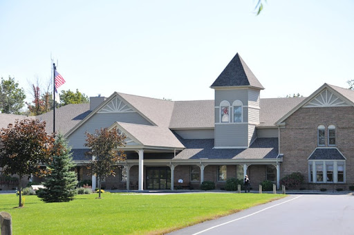 A modern church building surrounded by lush green grass and trees.