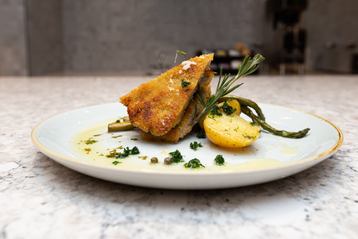 A beautifully plated gourmet dish featuring a crispy main course garnished with lemon, asparagus, and rosemary.