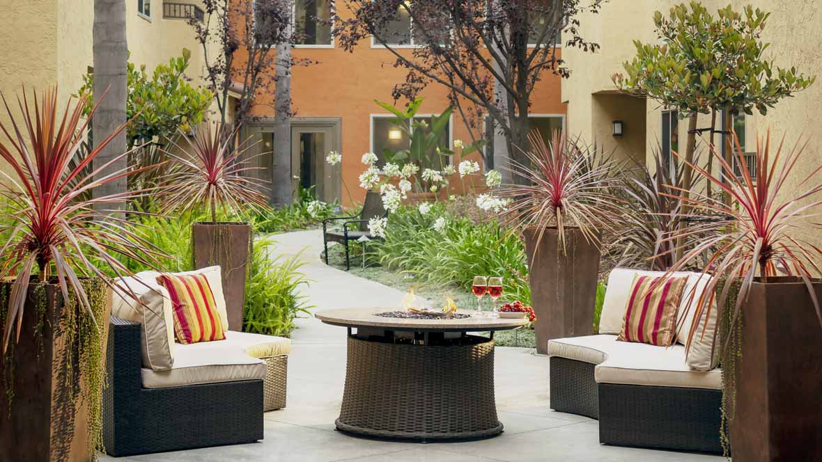 A cozy outdoor patio area with comfortable seating and lush landscaping.