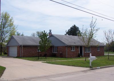 A suburban brick house with a driveway and a lawn.