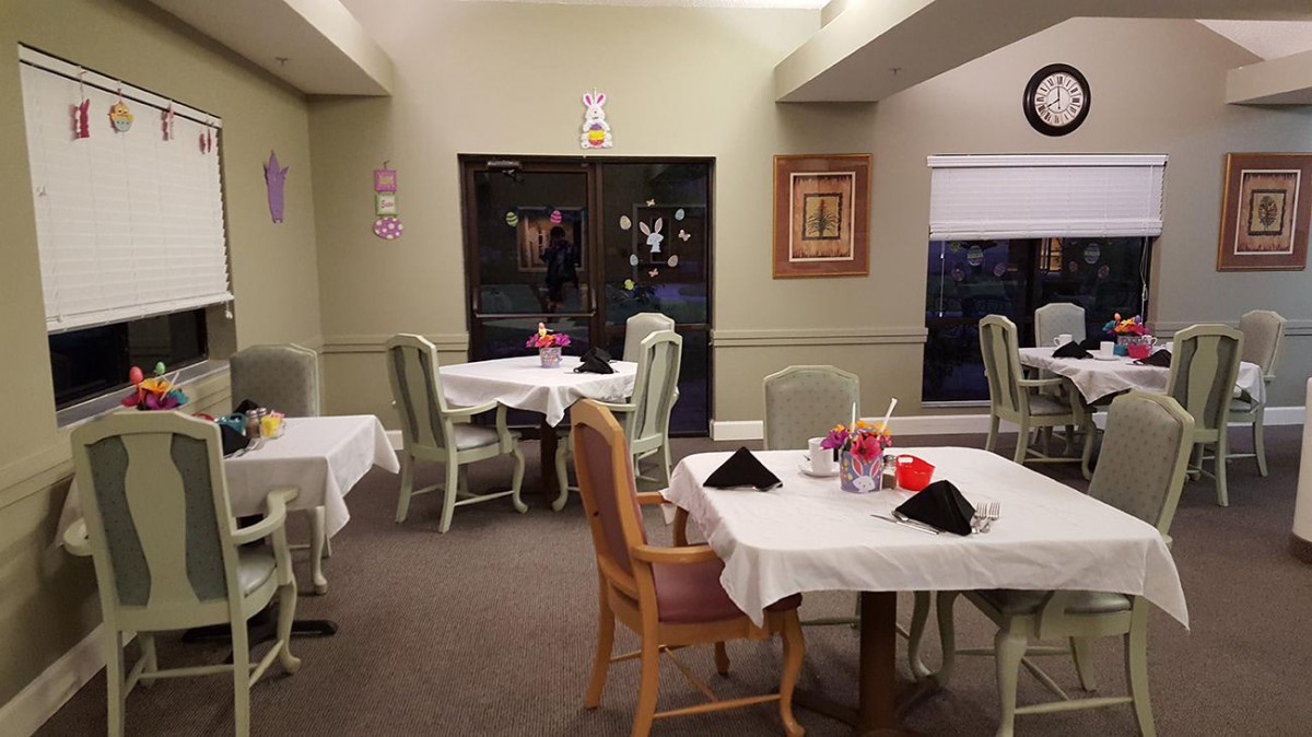 A cozy dining room with elegantly set tables and chairs, featuring warm interior decor.