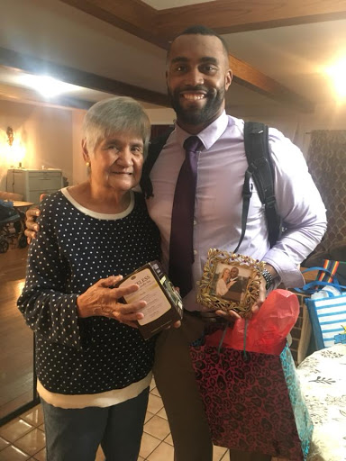 A joyful moment shared between an elderly woman and a young man, both holding gifts.