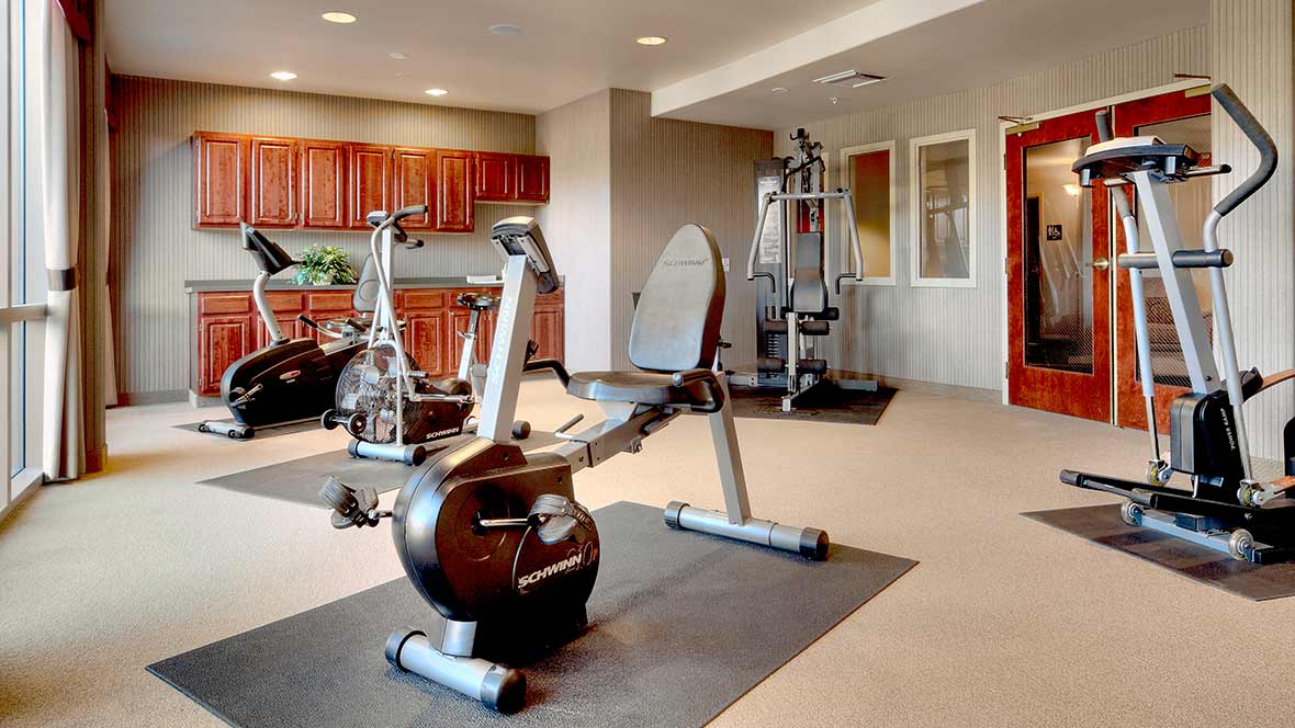 A home gym with various exercise equipment including stationary bikes and a weight machine.