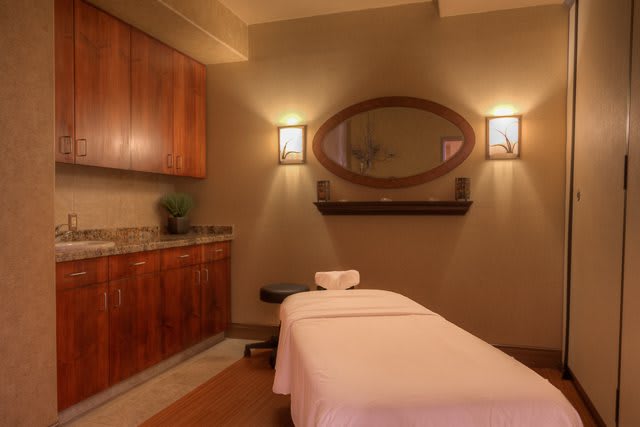 A serene massage room with ambient lighting and a comfortable bed.