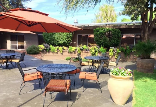 A cozy outdoor patio with tables and chairs, perfect for enjoying a meal surrounded by lush greenery.