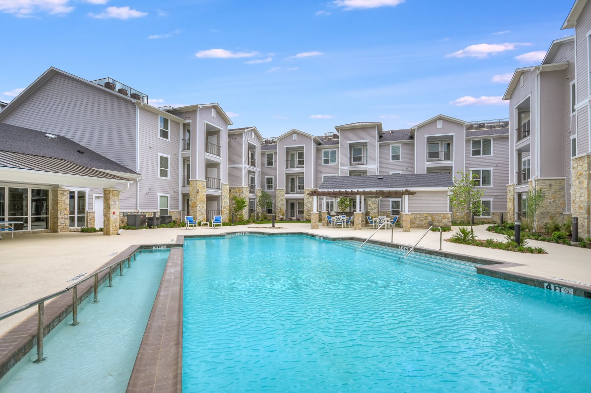 Modern apartment complex with a large outdoor swimming pool.