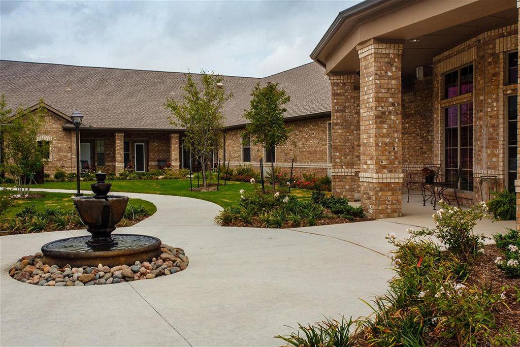 A beautifully landscaped courtyard with a brick building and fountain.