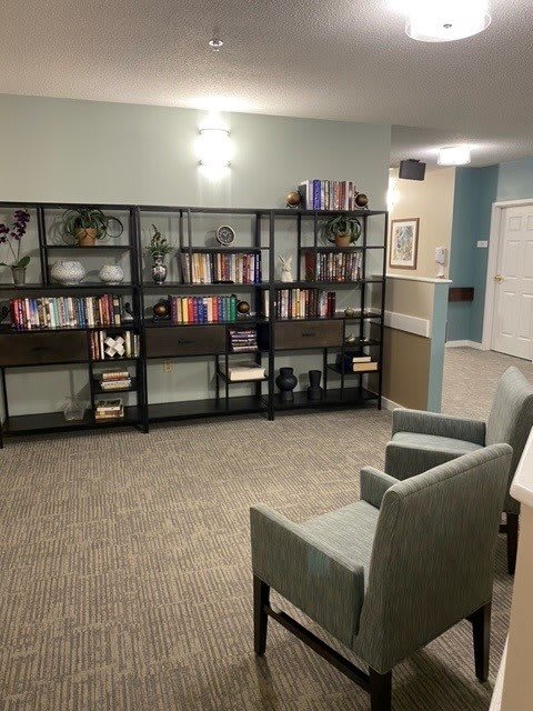 A cozy living room with a large bookshelf and comfortable chairs.