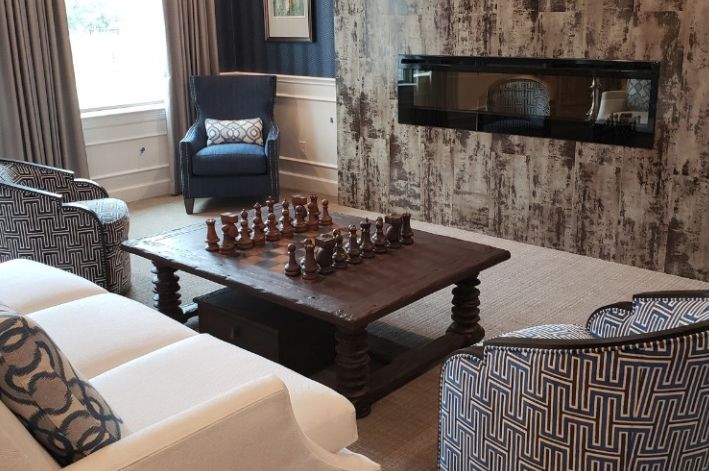 A cozy living room with a large chess set on a wooden coffee table, featuring modern decor and a fireplace.