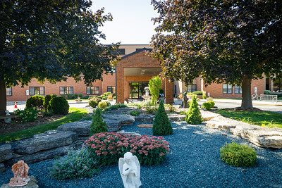A landscaped garden with blooming flowers and trees in front of a building entrance.