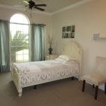 A cozy bedroom with a single bed, featuring large windows and minimalist decor.