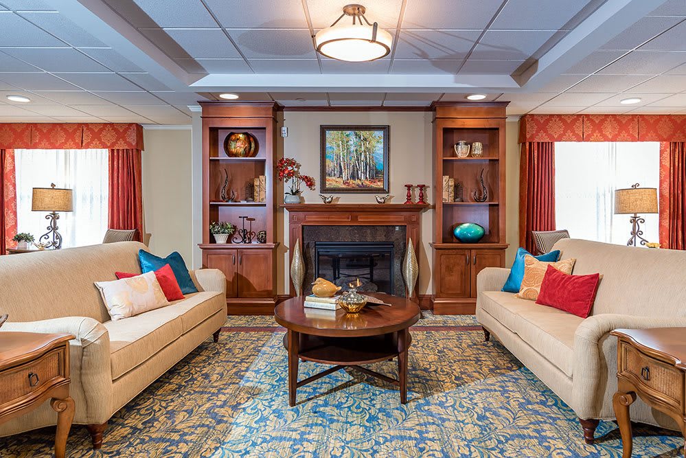 A cozy living room with two sofas, a fireplace, and decorated shelves.