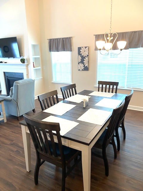 A modern dining area with a table set for six, adjacent to a cozy living space.
