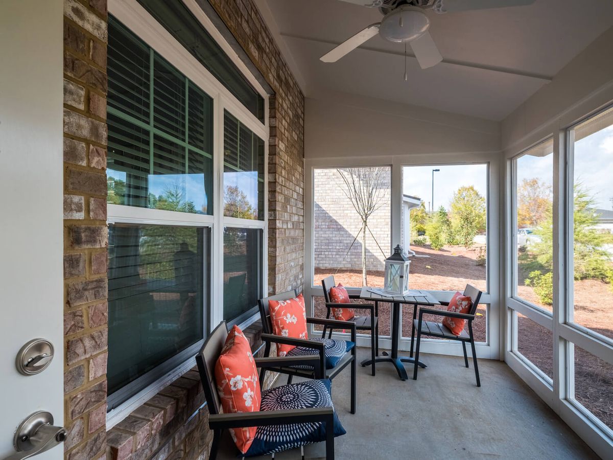 A cozy screened porch with comfortable seating and a ceiling fan.