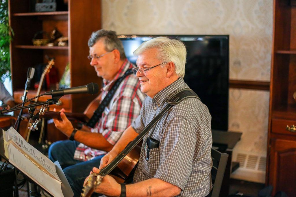 Two musicians playing guitars during an indoor performance.