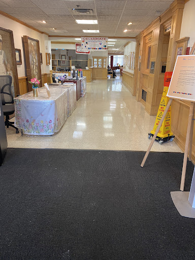 A spacious hallway in an office building, featuring tables on the sides and a cleaning sign.
