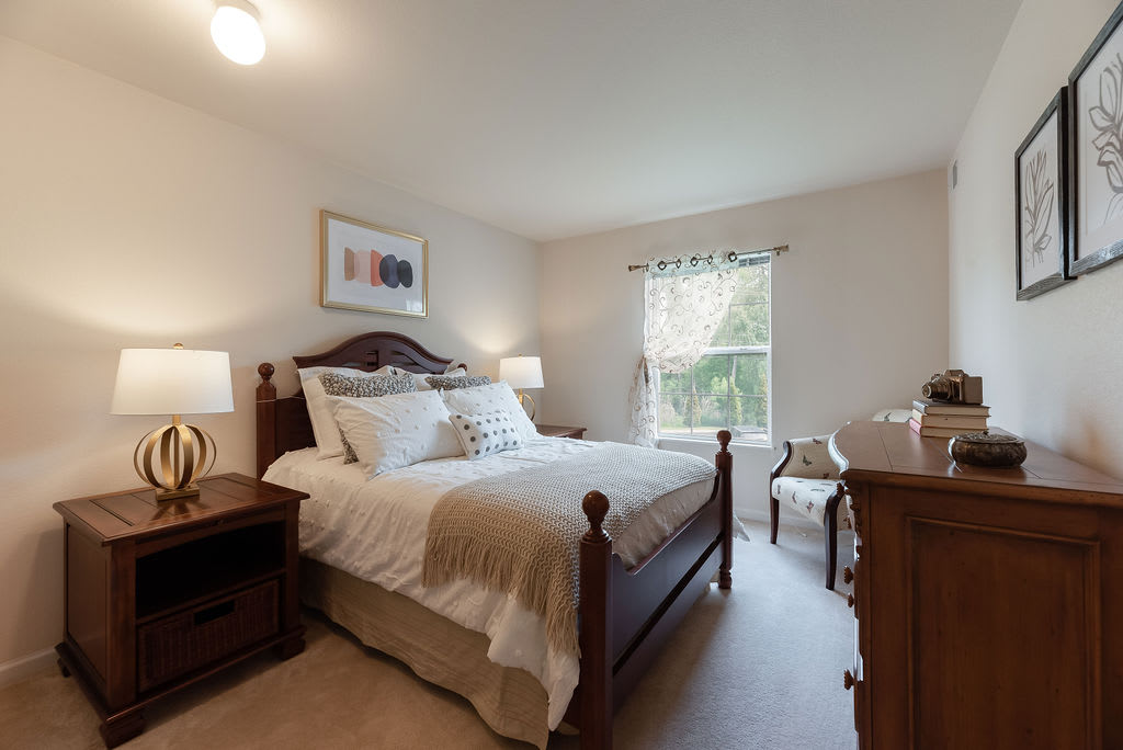 A cozy bedroom with a large bed, two nightstands, and a window letting in natural light.
