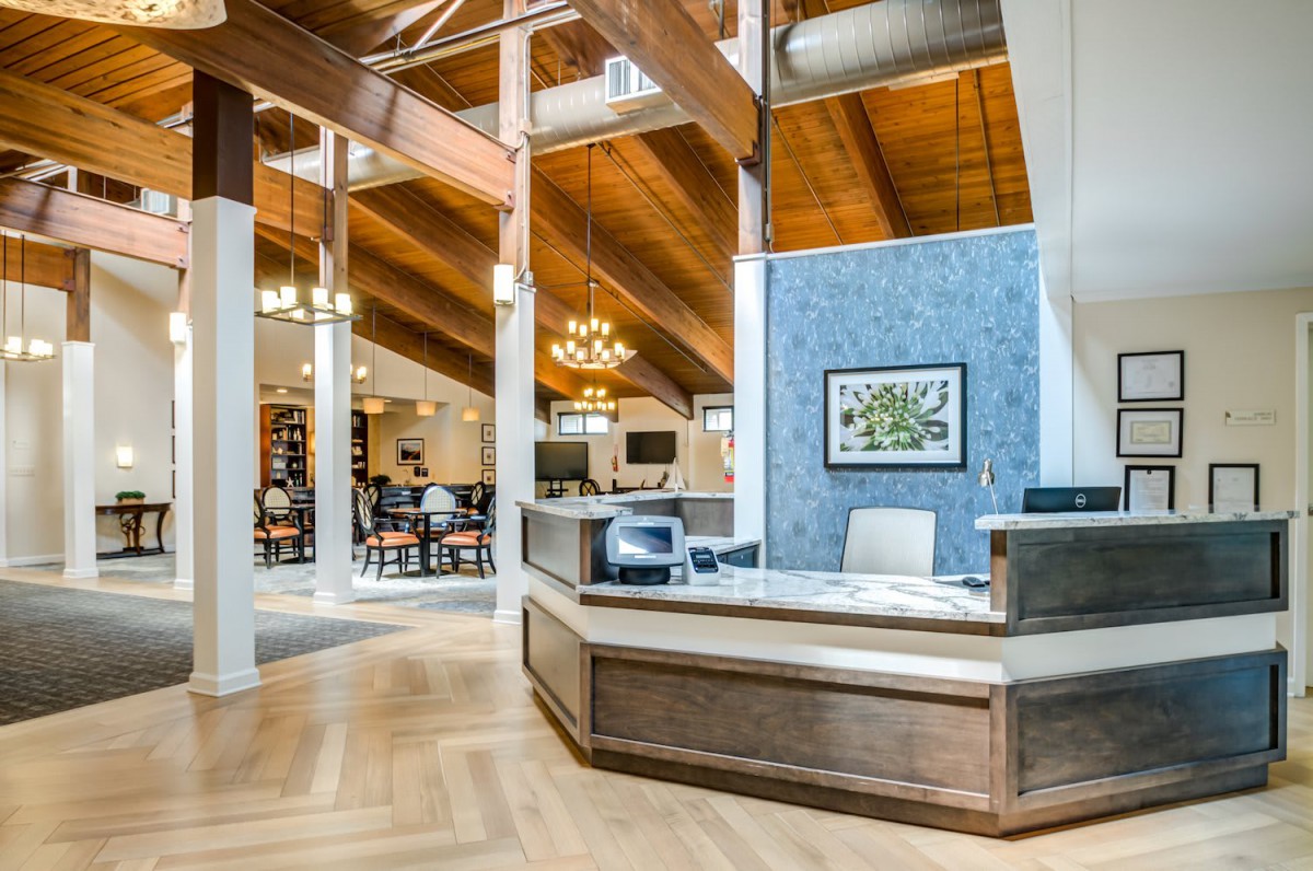 A modern reception area featuring a wooden ceiling, elegant chandeliers, and an open layout.