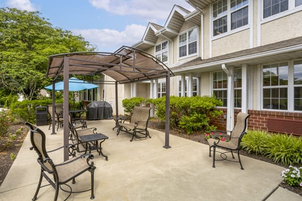 A sunny patio area with outdoor furniture and a gazebo in a residential setting.