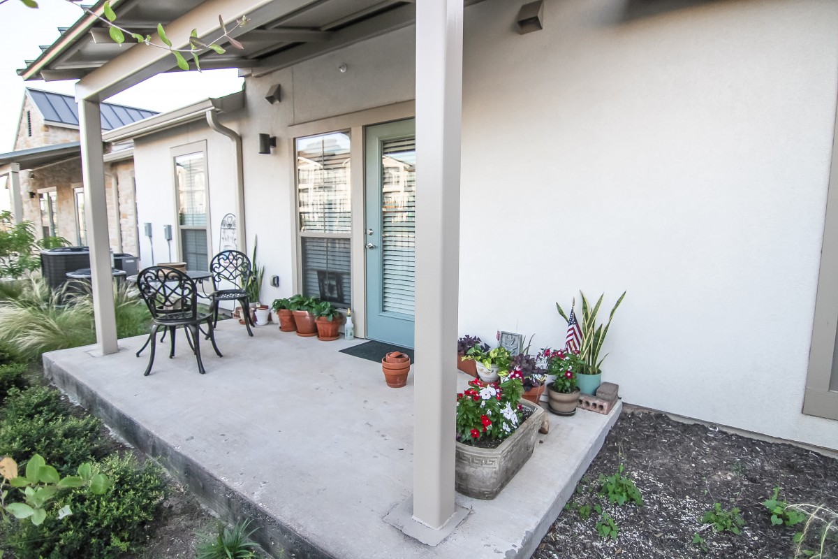 A cozy patio with potted plants and outdoor seating.
