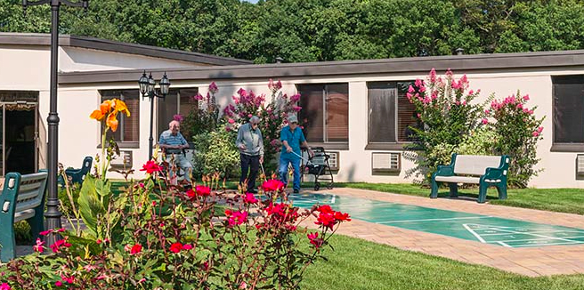 A group of people standing near a pool surrounded by red flowers and greenery.