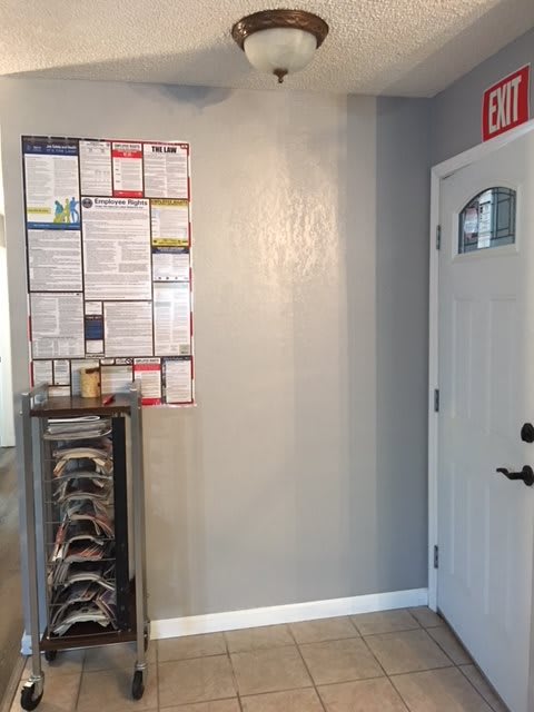An interior view showing a bulletin board filled with documents, a door, and a nearby rack.