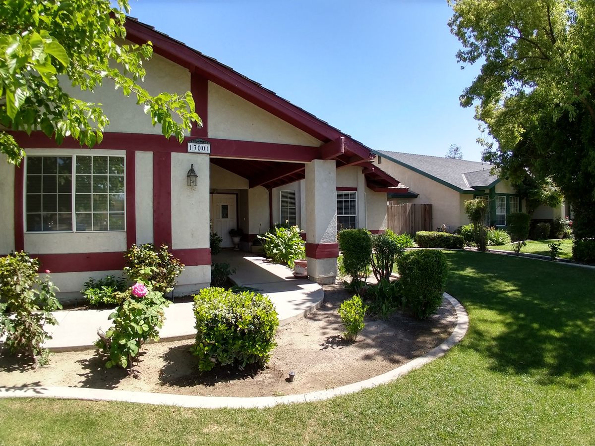 A charming residential house with well-maintained landscaping on a sunny day.
