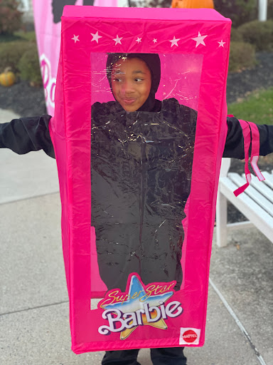 A child dressed up in a creative Barbie-themed costume, resembling a toy box.