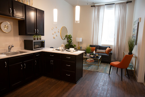 A cozy modern kitchen seamlessly integrated with a stylish living area, featuring sleek cabinetry and comfortable seating.
