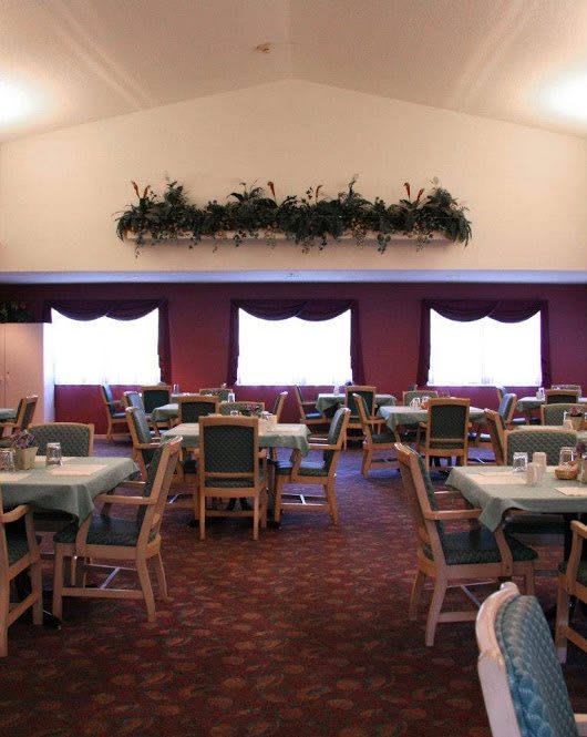 An empty dining room with neatly arranged tables and chairs, featuring decorative elements on the walls.