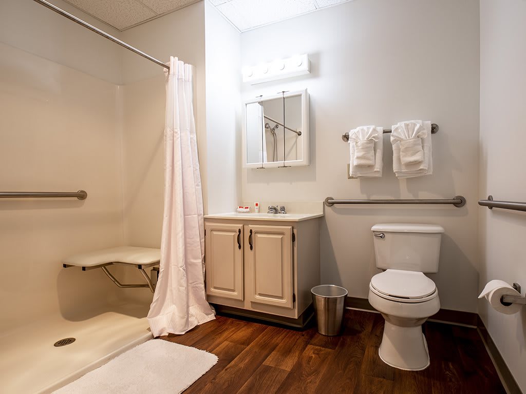 A clean and well-organized bathroom with a shower, toilet, sink, and mirror.