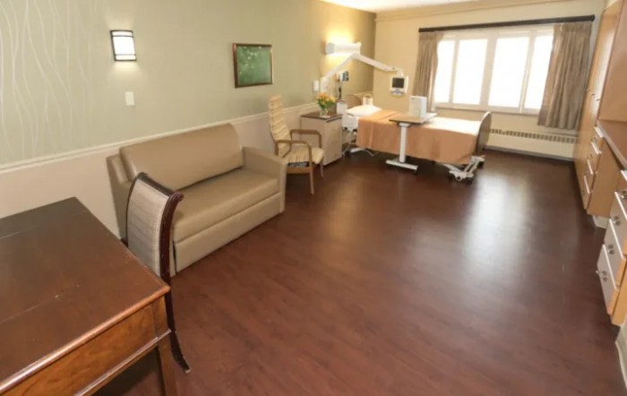 A clean and spacious hospital room with a patient bed and sofa.