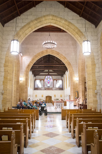 A serene view of the interior of a gothic-style church, featuring wooden benches and elegant lighting.