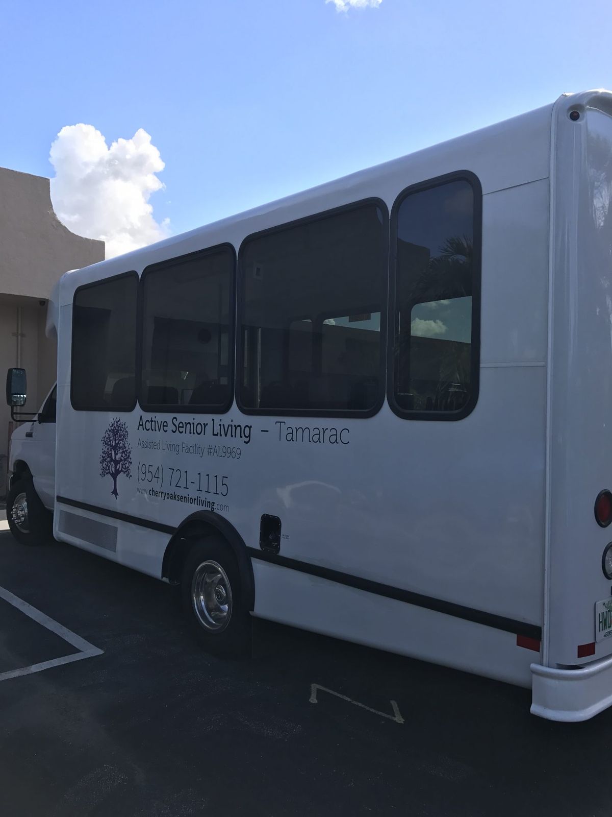 A white bus parked in a parking lot near a building.