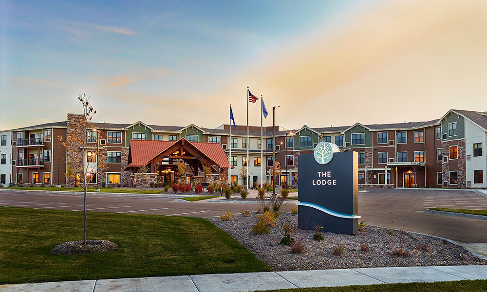 A hotel lodge with a welcoming entrance and landscaped surroundings, featuring flags and prominent signage in the front.