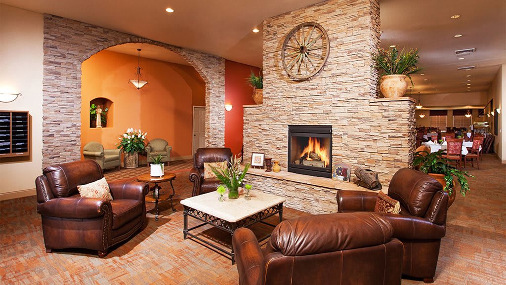 A cozy living room with a stone wall fireplace and leather seating.