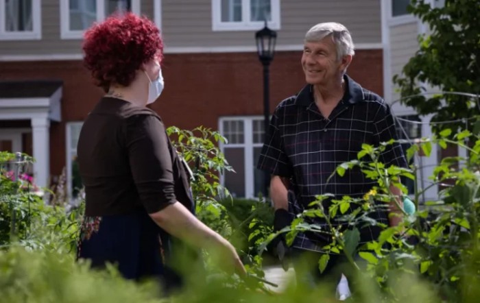 Two people having a conversation in a garden setting.