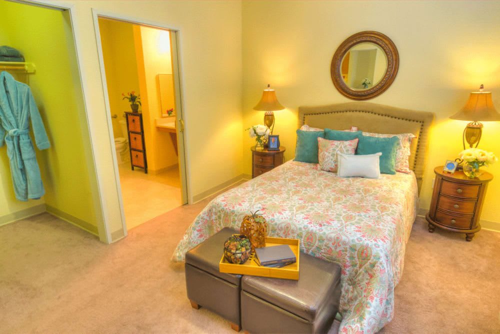 A cozy bedroom with a neatly made bed, decorative pillows, and a bedside lamp.