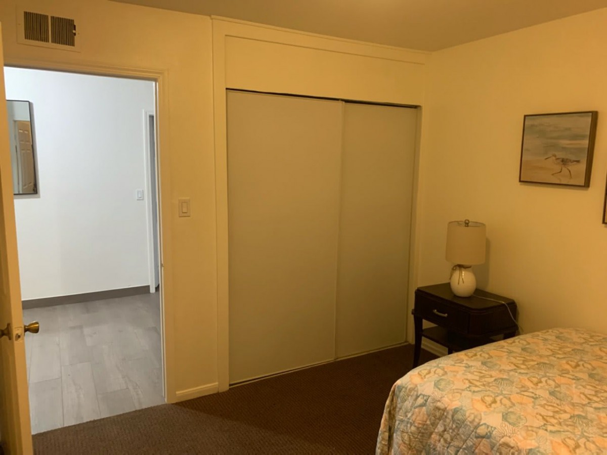 A cozy bedroom with a bed, side table, and sliding closet doors.