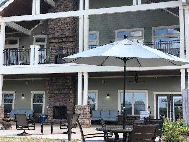 An outdoor patio area featuring tables, chairs, a large umbrella, and a multi-story building in the background.