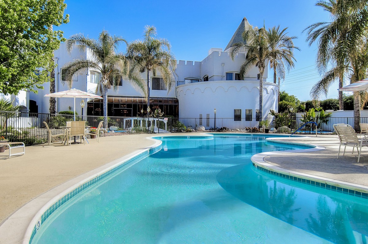A luxurious house with a stunning outdoor swimming pool and palm trees.