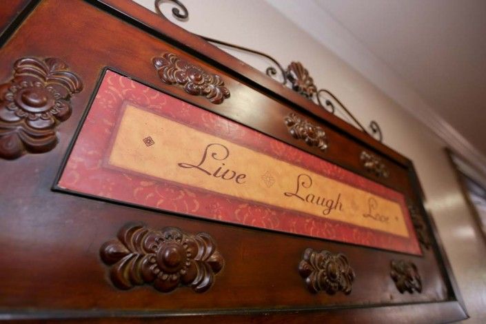 A decorative wooden sign with the inspirational quote 'Live Laugh Love' in an ornate design.