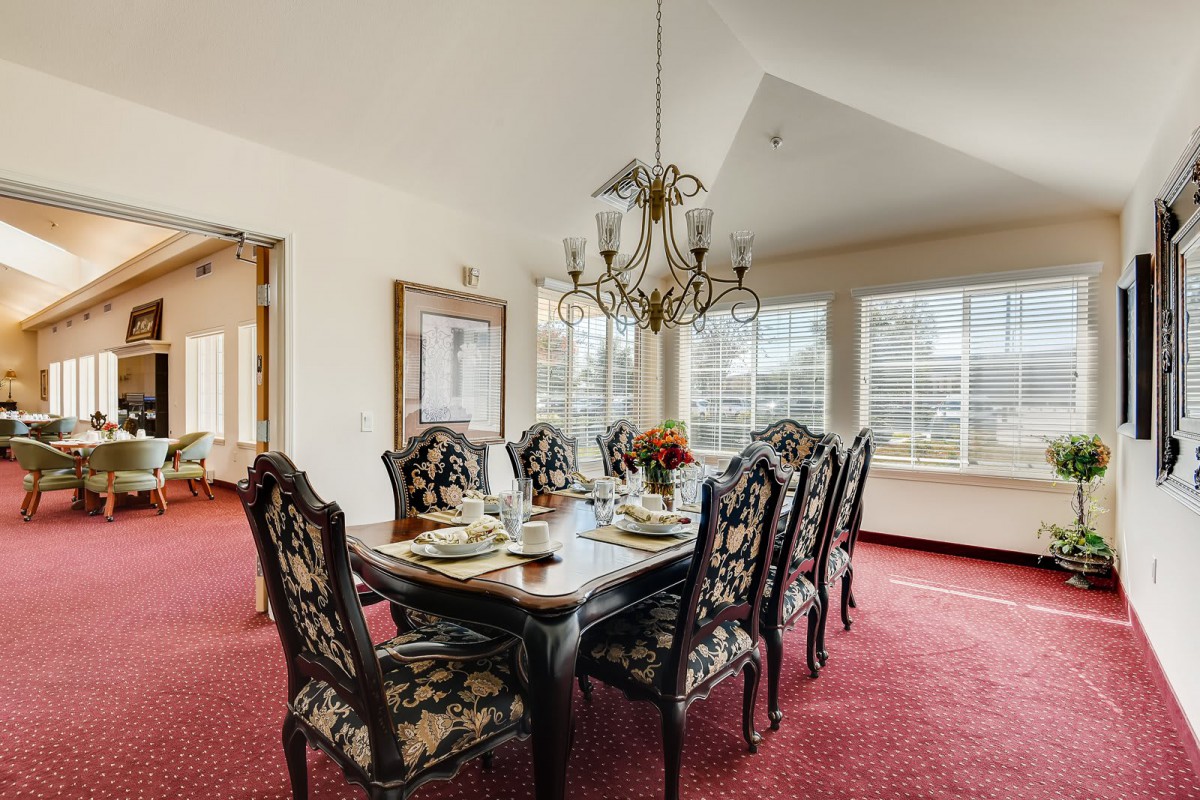 A well-appointed dining room with an elegant chandelier, ornate chairs, and large windows.