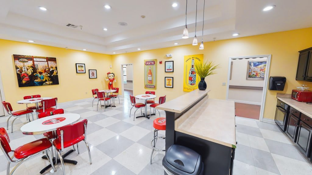 A retro-style diner interior with red chairs, tables, and yellow walls adorned with vintage decorations.