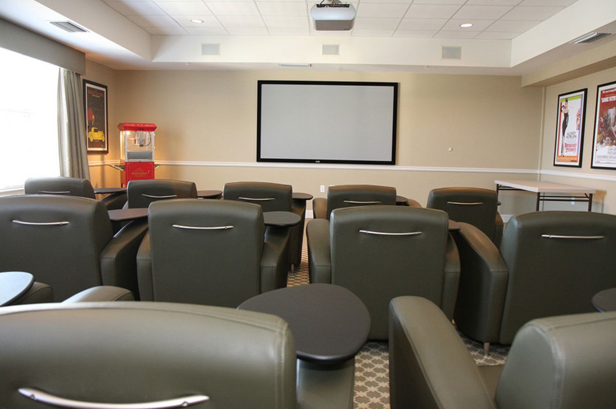 A small theater room with comfortable seating and a popcorn machine.