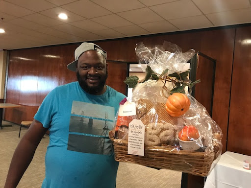A joyful man proudly holding a beautifully decorated gift basket.