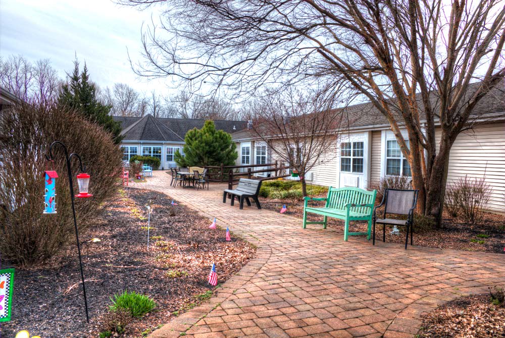 A serene courtyard garden with a paved pathway and colorful benches.
